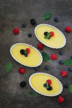 Homemade Classic French Creme Brulee topped with fresh berries and mint, top down view