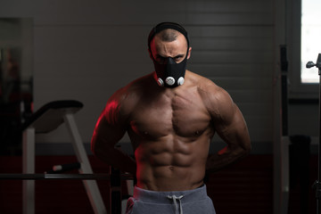 Fototapeta na wymiar Muscular Man Flexing Muscles In Elevation Mask