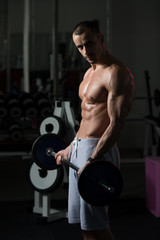 Obraz na płótnie Canvas Muscular Man Exercising Biceps With Barbell