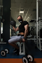 Fototapeta na wymiar Man With Dumbbells Exercising Biceps In Elevation Mask