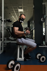 Fototapeta na wymiar Bodybuilder Exercising Biceps With Dumbbells In Elevation Mask