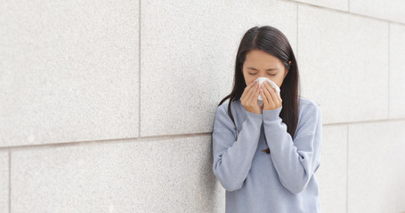 Woman sneezing at outdoor