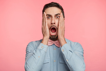 Terrified shocked scared male keeps mouth opened, looks with amazed expression at camera, isolated...