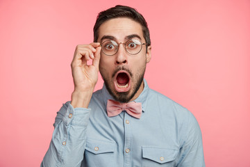 Portrait of shocked stupefied young bearded male model stares at camera as forgets some importnat...