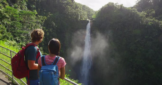 Hawaii Couple tourists on Hawaii by famous hawaiian waterfall on Big Island. Tourist girl pointing at Akaka Falls waterfall on Hawaii, Big Island, USA. Travel tourism young people concept - Powered by Adobe