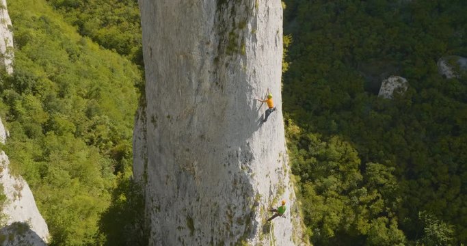 Aerial side shot of amazing climbers climbing the rock in nature on a summer day.
