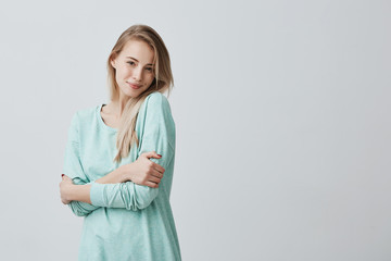 Isolated shot of attractive european student girl with blonde long hair looking and smiling broadly...