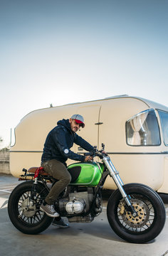 Stylish man on motorcycle near a van