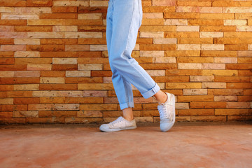 Old White Shoes. Woman Wear White Sneaker and Blue Jeans on Orange Brick Wall Background Great for Any Use.