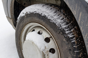 Front wheel of the truck covered with snow closeup