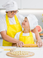 Happy grandmothers and grandson cook dinner in the kitchen