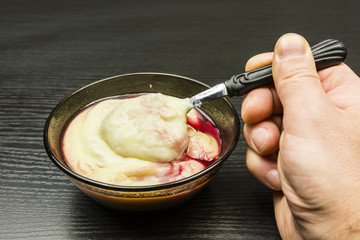 Teaspoon with pudding and raspberry juice from a bowl.