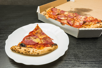 Pulled out a portion of pizza on a plate from the box.