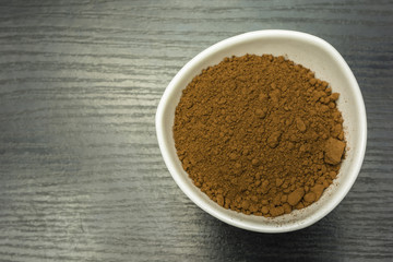 Cocoa powder in a bowl on the table. View from above.