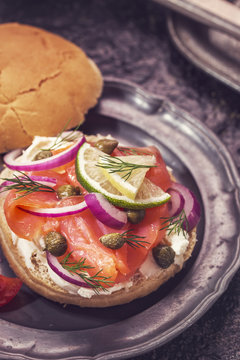 Burger with smoked salmon and cream cheese on vintage plate, close-up