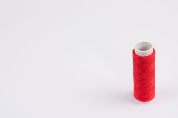 One red bobbin of new colorful thread on white background
