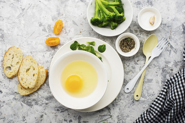 Ingredients for cooking scrambled eggs or omelets with green herbs, fresh vegetables, broccoli and turmeric as a healthy breakfast or lunch option. View from above. Against a light background.