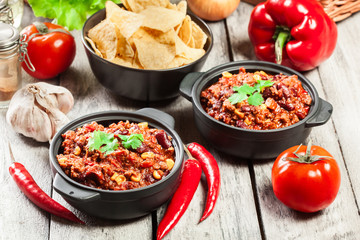 Bowls of hot chili con carne with ground beef, beans, tomatoes and corn