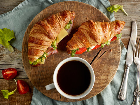 two croissant sandwiches on wooden table