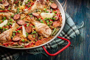 Traditional paella with chicken legs, sausage chorizo and vegetables served in paellera