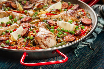 Traditional paella with chicken legs, sausage chorizo and vegetables served in paellera