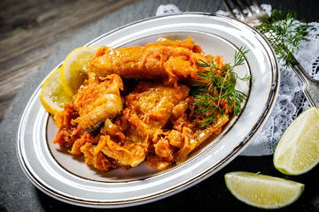 Fish in vegetable sauce on wooden background