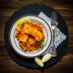 Fish in vegetable sauce on wooden background