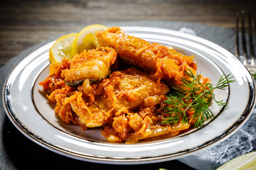 Fish in vegetable sauce on wooden background
