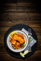 Fish in vegetable sauce on wooden background