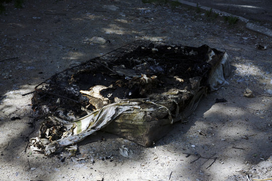 a burned mattress lies on the pavement after a fire .