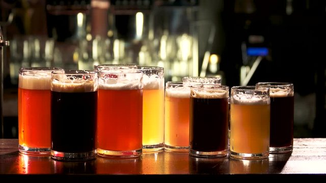 Barman serves up glasses of draft beer. Bartender put many different sorts of beer on the table.