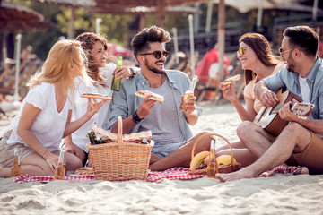 Happy people eating pizza and have fun on the beach.
