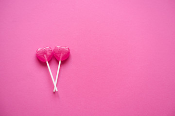 Couple of 2 heart shaped lollipops on pink. Valentine's day background, greeting card concept.