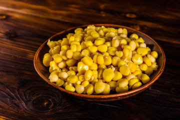 Ceramic plate with canned corn seeds on wooden table