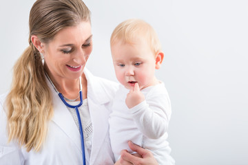 Portrait of a dedicated female physician and pediatric care specialist, smiling while holding a cute and healthy baby girl at the hospital or in a medical healthcare center