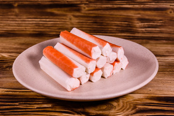 Ceramic plate with crab sticks on wooden table