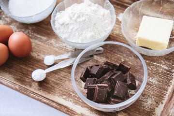 Baking ingredients for chocolate cake muffins or cookies lying ready on wooden kitchen tray. Mise...