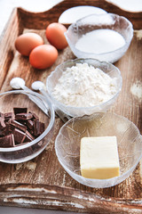 Baking ingredients for chocolate cake muffins or cookies lying ready on wooden kitchen tray. Mise en place, white background, measured ingredients.