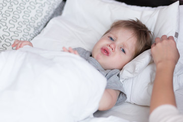 Little kid boy with sore throat cough in the bed close-up