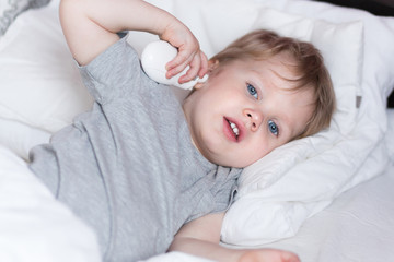 Measuring baby's temperature with contactless digital infrared thermometer in the ear. 2 years old kid measures its temperature in the ear himself