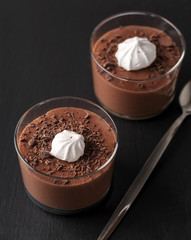 Chocolate mousse in a glasses on a black stone background.