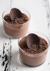 Chocolate mousse in a glasses on a white wood background.