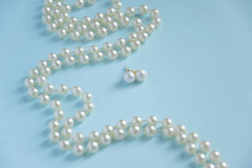 White pearls on blue background - luxury fashion concept