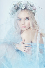 Charming fairy woman in a blue ethereal dress and a wreath on her head on white background, gentle...