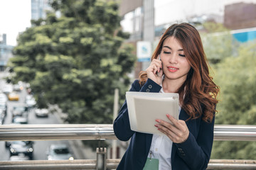 Portraits of beautiful asian woman look confidence is standing and holding cellphone . she using smartphone calling to conversation with customer.
