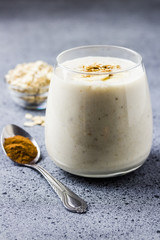 Cinnamon roll banana oat smoothie in glass on concrete background. Selective focus, space for text. 