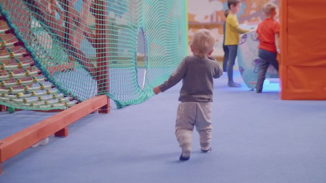 Back view of blond toddler running and his mom following him