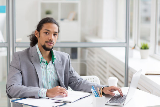 Young serious specialist in formalwear planning or carrying out his work