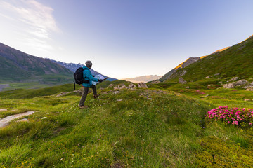 Fototapeta premium Hiker backpacker with trekking map at sunrise in the italian french Alps.