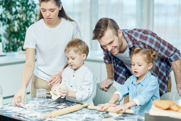 Obraz premium Two cute siblings helping their parents make homemade pastry in the kitchen